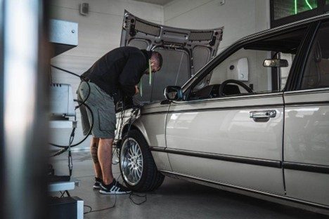 Muž kontrolujúci technický stav motorového vozidla v sivej farbe v autoservise Biga